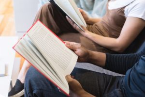 people sitting side by side with open books